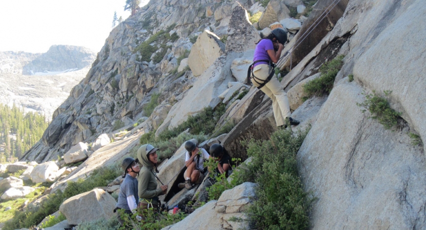 a group of students laugh as they rock climb on an outward bound course for bipoc